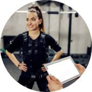 eine Person im EMS-Trainingsanzug und davor hält der personal coach ein iPad in der Hand